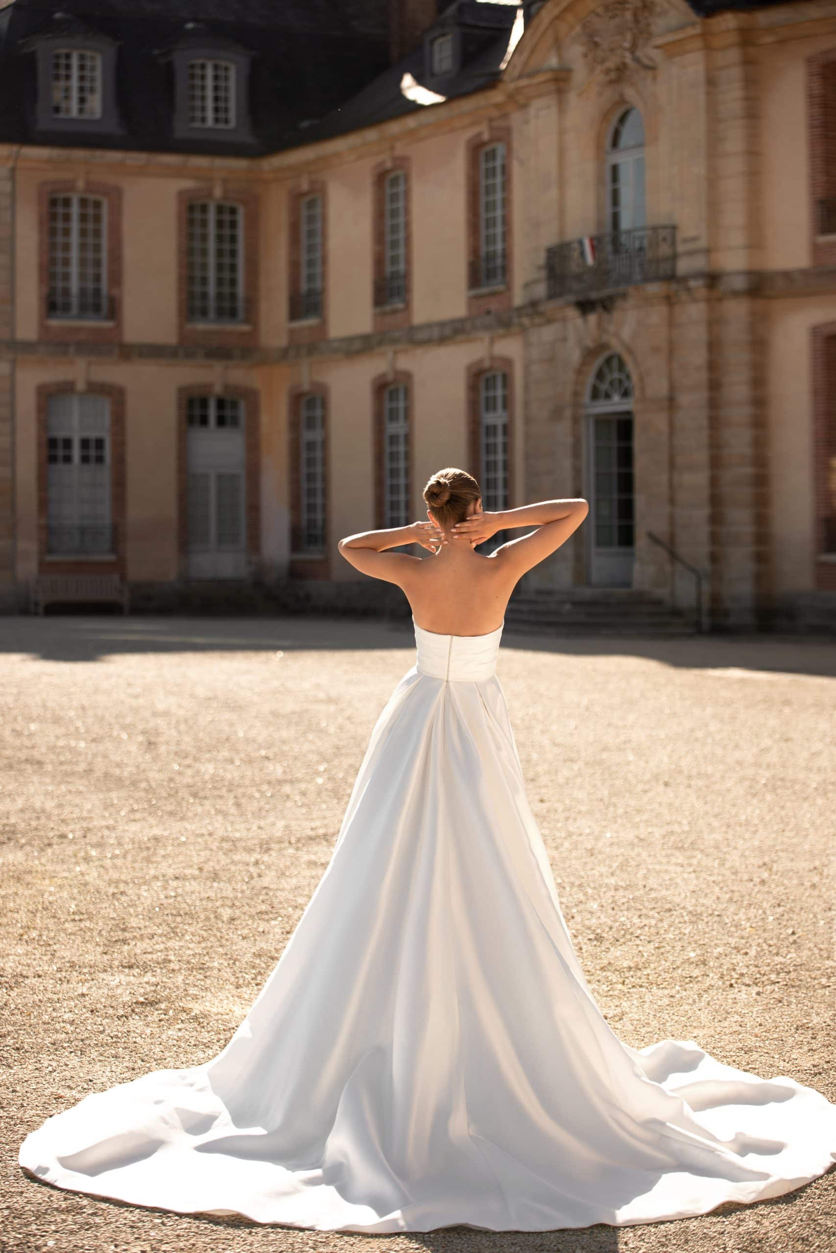 Bild von hinten: schlichtes und elegantes weißes Brautkleid mit langer Schleppe und trägerlos